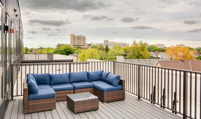 a deck with a couch and a table on it with trees and buildings in the background